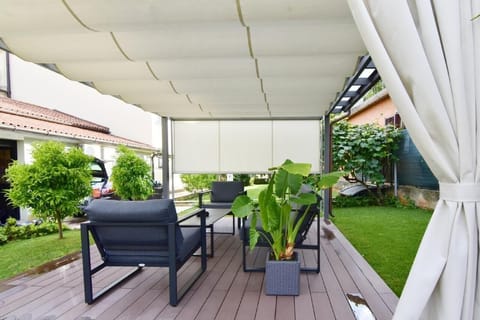 The beautiful covered terrace in the garden equipped with garden furniture.