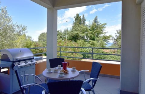 The covered terrace equipped with a table and chairs and a portable barbecue.