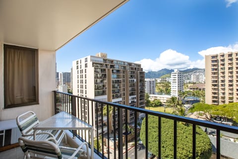 This urban cityscape shows the property's central location among mid-rise buildings, with mountain vistas marking the tropical horizon beyond the neighborhood greenery.