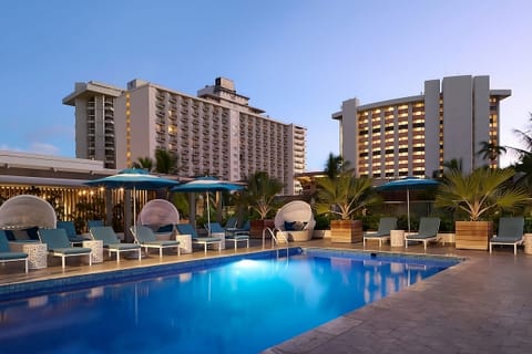Unwind at dusk beside the glowing pool and loungers.