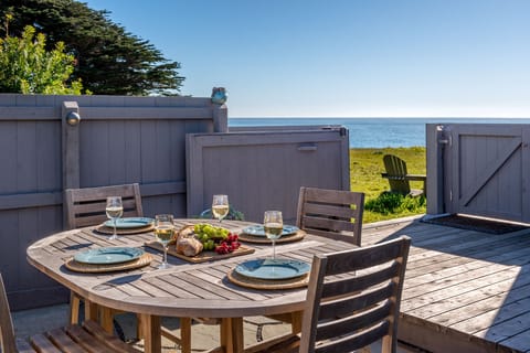 A teak dining table set within the private courtyard offers an open view toward the ocean, creating an effortless setting for unhurried meals with the bluff trail just beyond.