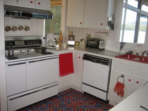 Kitchen in Little House with kitchen equipment, dishes, cutlery and microwave.