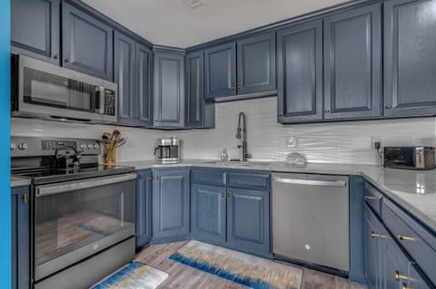 This stylish kitchen pairs navy cabinetry with brass hardware and sleek appliances. A clean backsplash and modern fixtures add polish to your seaside cooking space.