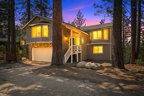 Beautifully lit at dusk, the "Pines On The Lake" cabin offers a warm and inviting mountain retreat nestled among towering Tahoe pines.