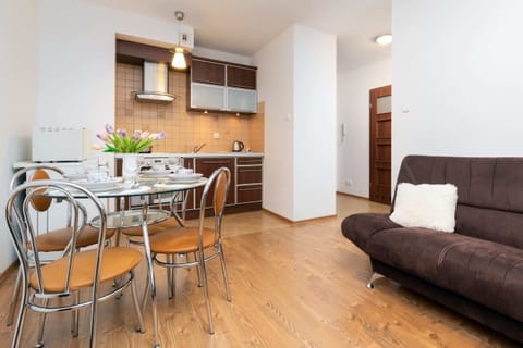 A dining and living area featuring a dining set, sofa, and cozy furnishings with wooden flooring.