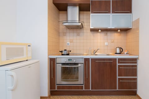 A compact kitchen equipped with wooden cabinets, a stovetop, and essential appliances.