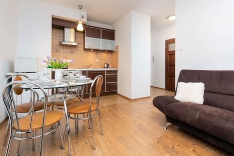 A dining and living area featuring a dining set, sofa, and cozy furnishings with wooden flooring.
