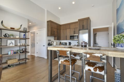 Open kitchen layout with custom shelving and cowhide barstools.