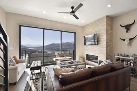 Sunlit living area with mountain views, leather seating, and stone fireplace.