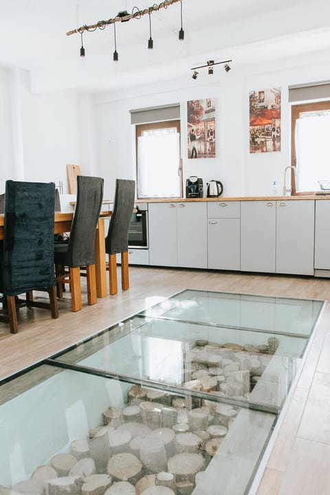Kitchen with a glass floor looking into a bed of seasoned logs