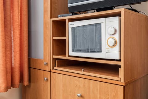 A close-up of a corner with a microwave on a small cabinet, adding a functional and nostalgic touch to the kitchen.