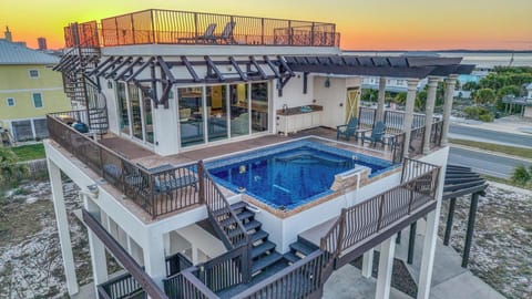Elevated beachside retreat featuring a stunning rooftop pool and deck with sunset views over the coastal neighborhood.