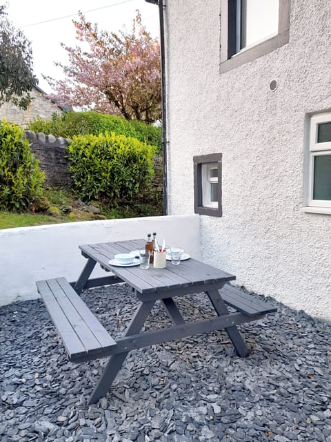 The back garden is set up with a picnic style bench for good weather use
