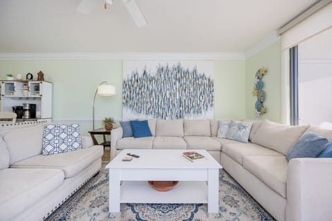 Unwind on the spacious sectional sofa, surrounded by coastal decor and inviting natural balcony light