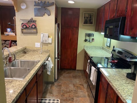 Full kitchen with full sized refrigerator, microwave, stove/oven, dishes