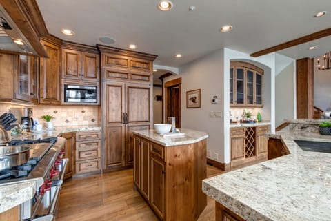 Fully equipped kitchen with Wolf appliances, Sub-Zero fridge, double ovens, stone countertops, island, and bar seating for 5.