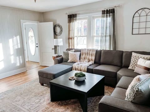 - Living room with sectional sofa and soft throw blankets - Bright windows and modern wall decor create cozy style - Spacious spot to relax and enjoy quality family time