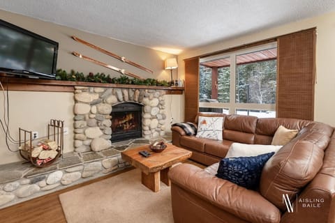 Living room with a smart TV, a cozy sectional and decorative fireplace (glow logs only due to strata regulations.)