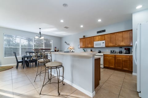 Open kitchen and dining area with breakfast bar seating, full appliances, and natural light.