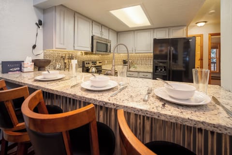 Your fully equipped kitchen features granite counters, modern appliances, and a breakfast bar where you can enjoy morning coffee.