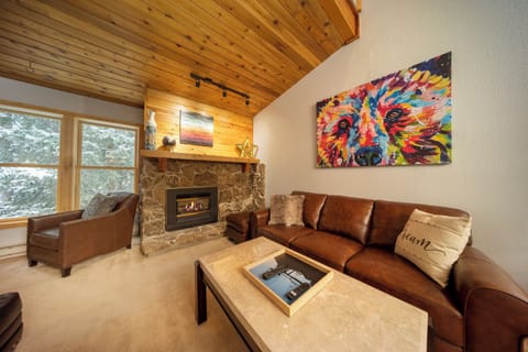 Cozy up by the stone fireplace in your stylish living room, where rich leather seating meets vibrant artwork.