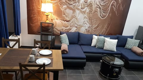 Widoczna sofa z funkcją spania, stół, oświetlenie nocne oraz unikatowy stolik