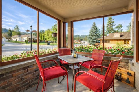 Your private enclosed patio offers peaceful dining with vibrant red chairs and panoramic mountain views through floor-to-ceiling windows.