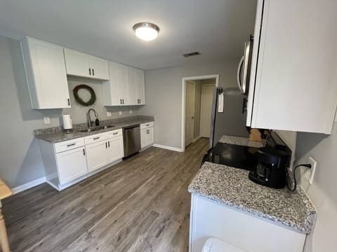 Full kitchen equipped with dishes, cookware, coffee pot, and utensils.