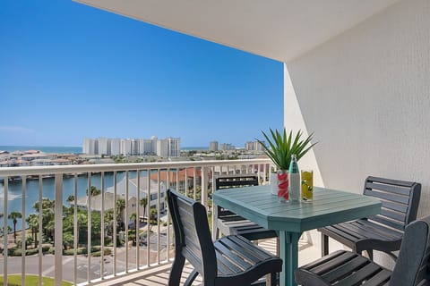 Elevated beachfront balcony with city views and outdoor dining table for four guests.