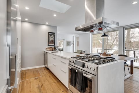 Your gourmet kitchen features premium stainless steel appliances, sleek white counters, and a stunning gas range perfect for cooking memorable meals together.