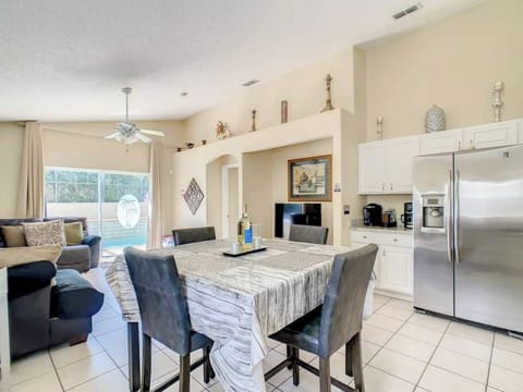 Our  modern kitchen and dining area. A dining table with chairs is in the foreground, while a kitchen with appliances and a living room area are visible in the background.