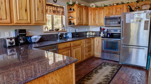 The kitchen is equipped with stainless appliances: An electric range, refrigerator, dishwasher, and microwave, and a drip coffeemaker.