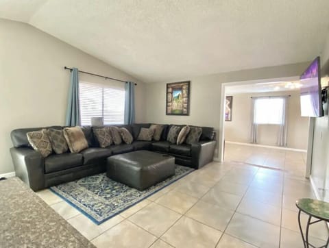 Large living room with leather sectional sofa, ottoman, and Smart TV