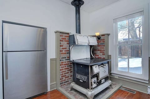 - Discover rustic charm with a rare antique cast iron stove framed in brick
- Sunlight pours through tall windows, blending nostalgia with natural light
- Modern stainless steel fridge offers convenience beside vintage flair