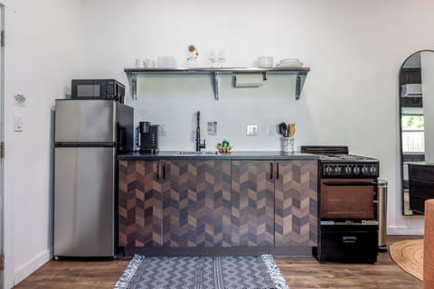 A cute and quaint kitchen fully equipped with a fridge, sink, and small stove 