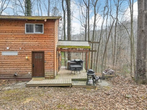 Deck off the side of the cabin with seating, a grill, fire pit area, and hot tub