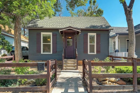 Charming cottage welcomes with a red front door, porch steps, and fenced garden beds out front. Arrive, drop your bags, and follow the walkway right up to the entrance.
