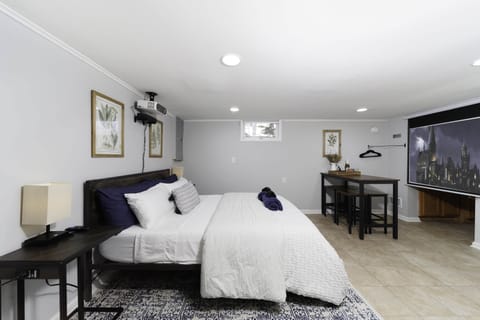 The bedroom features black-out blinds, a projector, Roku soundbar and an 84" screen