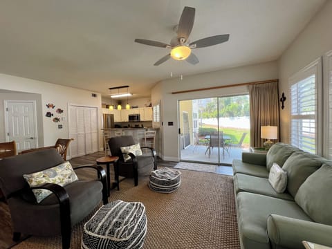 Relax in your spacious open-concept living room with comfortable seating, modern kitchen access, and sliding doors to your private patio.