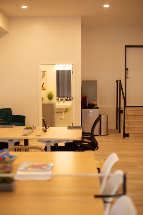 Office photo with table, two desks, half bath, mini fridge, and door to garage