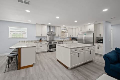 An open kitchen with sleek stainless steel appliances, illuminated by warm, stylish lighting that adds a touch of charm.