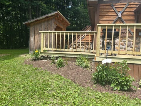 Porch with picnic bench seating & a gas grill +wood shed for woodstove in winter