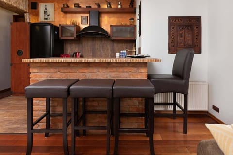 Traditional-style kitchen with wooden cabinetry, a black refrigerator, and vibrant red appliances, including a toaster and kettle.