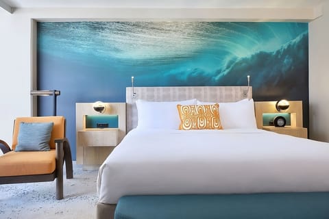 Unwind in a serene room beneath a dramatic ocean mural.