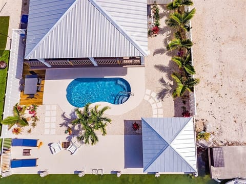 A stunning aerial perspective showcasing the home's canal-front location, private pool, and tropical outdoor spaces.