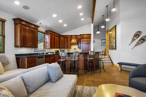 Relax in your spacious open-concept living area where rich wood cabinetry meets modern comfort—perfect for gathering around the breakfast bar. Unit A