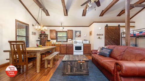 One large room with a full kitchen, large dining table, couch, and beds.