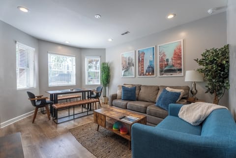 Living room + dining room that has comfortable seating, mounted tv, and games.
