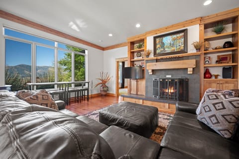 Experience the cozy living room, outfitted with plush seating, a fireplace, an expansive smart TV, and windows that frame the breathtaking mountain vistas.