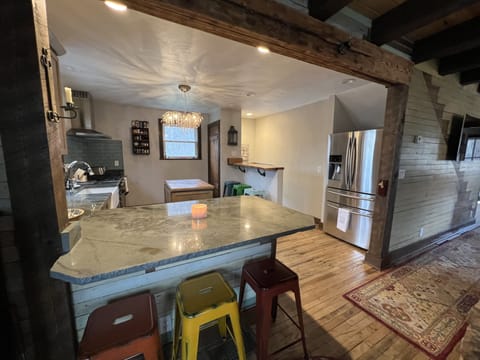 A granite island has 3 stools and a live edge bar top with 3 tall stools.